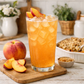 Sunhollow peach cobbler loaded tea in tall iced glass with cozy peach dessert styling and warm bakery potion vibes