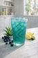 Blue iced drink in a glass with lemons and blueberries on a wooden surface

