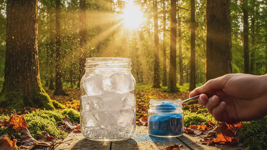 Blue instant tea powder being added to a mason jar filled with ice in a sunlit forest, showcasing a magical hydration drink preparation.